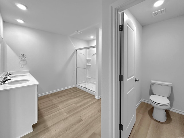 bathroom with a shower with door, vanity, wood-type flooring, and toilet