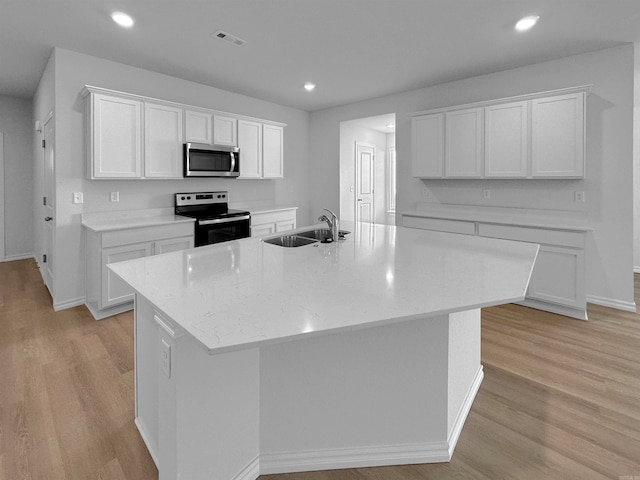 kitchen with white cabinetry, light wood-type flooring, appliances with stainless steel finishes, and an island with sink