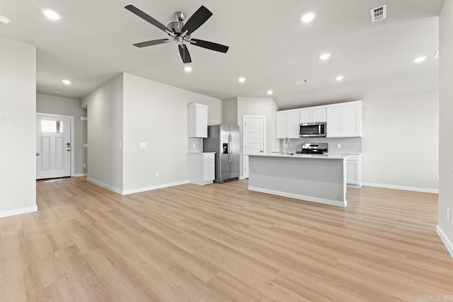 unfurnished living room with light hardwood / wood-style floors, sink, and ceiling fan