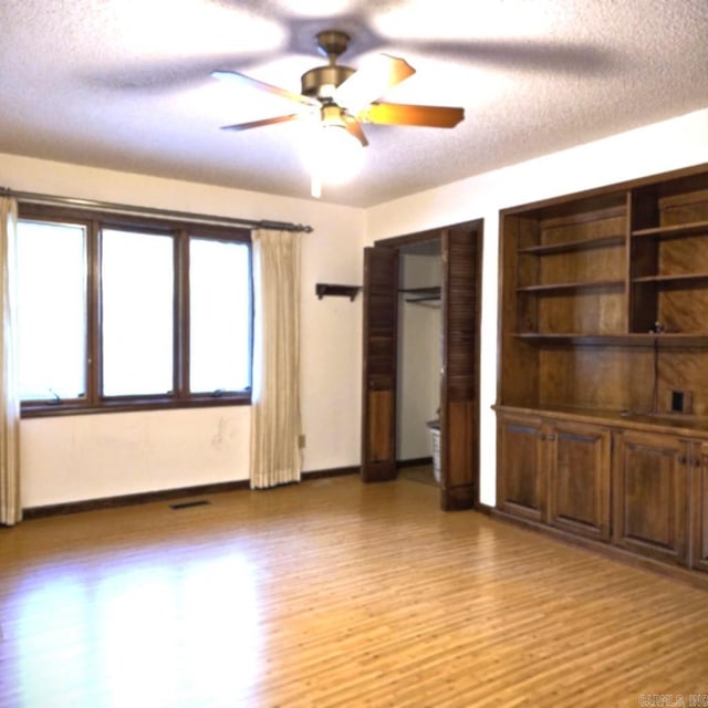 unfurnished room featuring ceiling fan, light wood-type flooring, and a textured ceiling