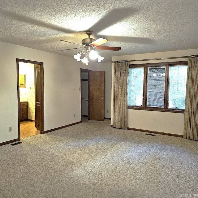 unfurnished bedroom featuring ceiling fan, light carpet, ensuite bath, and a textured ceiling