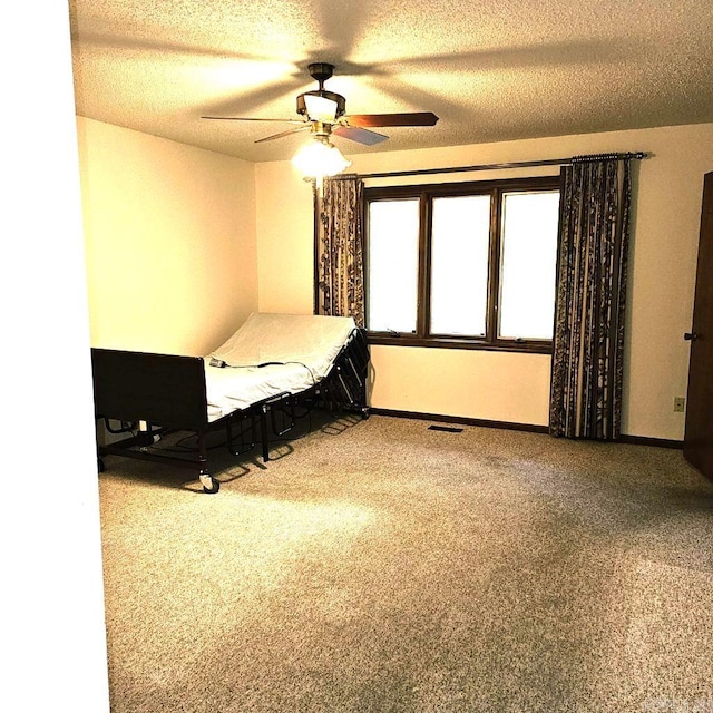 unfurnished bedroom with carpet flooring, ceiling fan, and a textured ceiling