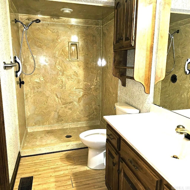 bathroom with tiled shower, hardwood / wood-style flooring, vanity, and toilet