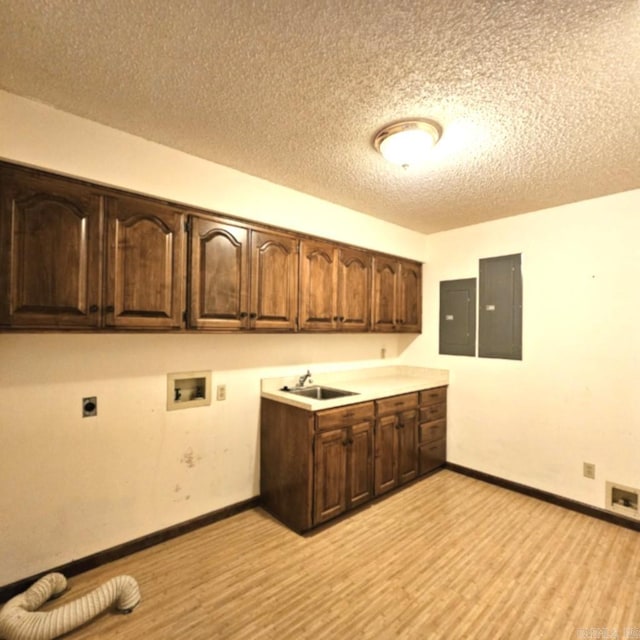 kitchen with light hardwood / wood-style flooring, electric panel, sink, and a textured ceiling