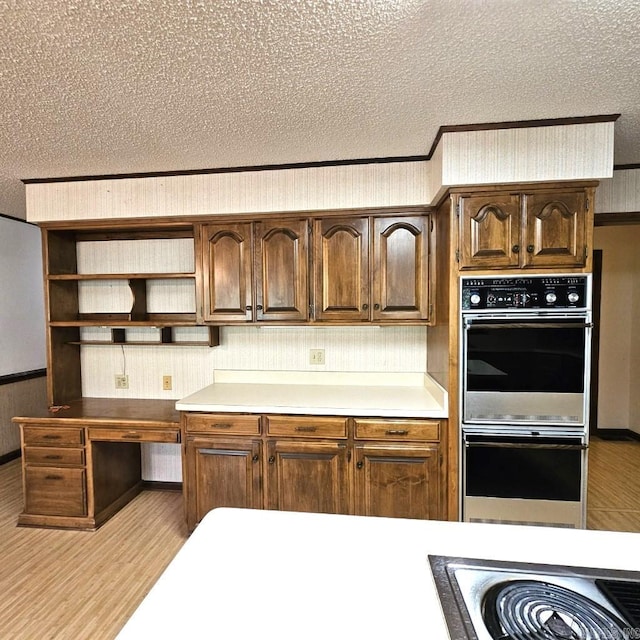 kitchen featuring light hardwood / wood-style floors, double oven, and a textured ceiling