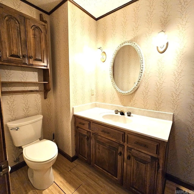 bathroom with hardwood / wood-style flooring, crown molding, vanity, and toilet