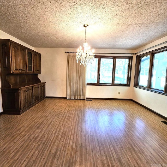 unfurnished living room featuring light wood-type flooring, a chandelier, and a textured ceiling