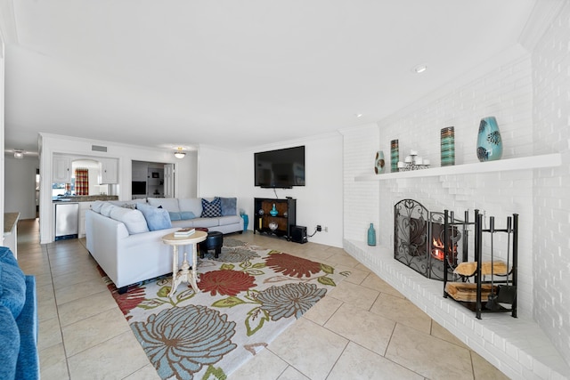 living room featuring a fireplace, crown molding, tile patterned flooring, and brick wall