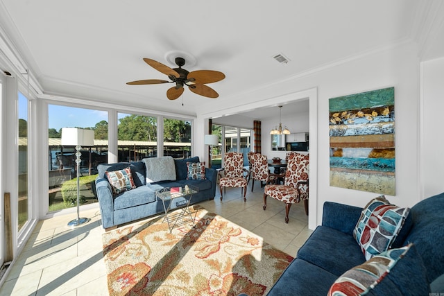 living room with ceiling fan with notable chandelier, a healthy amount of sunlight, crown molding, and light tile patterned floors