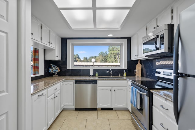 kitchen with appliances with stainless steel finishes, white cabinetry, sink, and tasteful backsplash