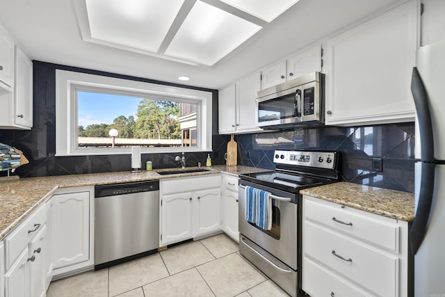 kitchen featuring sink, stainless steel appliances, backsplash, white cabinets, and light tile patterned floors