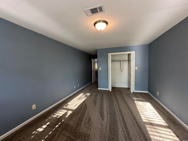 unfurnished bedroom with dark carpet and a closet