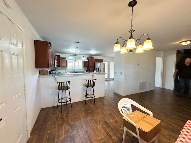 kitchen with kitchen peninsula, decorative light fixtures, dark hardwood / wood-style floors, and stainless steel refrigerator with ice dispenser