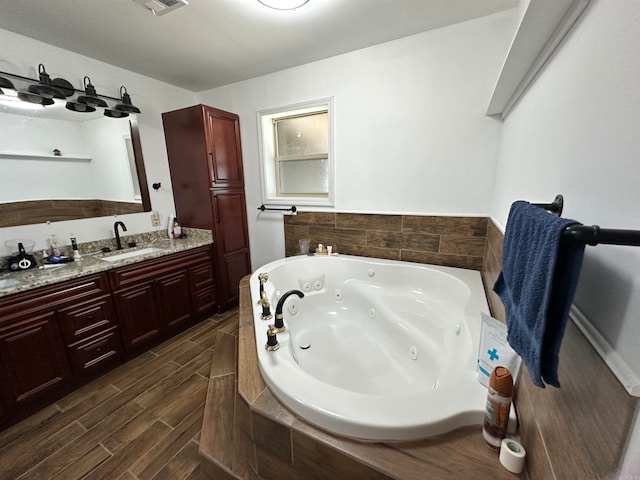 bathroom with tiled tub, vanity, and hardwood / wood-style flooring