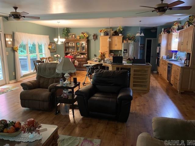 living room featuring ceiling fan with notable chandelier and light hardwood / wood-style floors