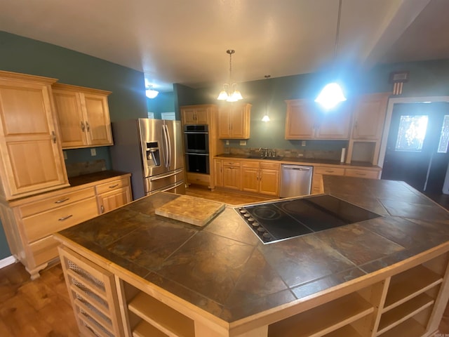 kitchen with light brown cabinetry, light hardwood / wood-style floors, decorative light fixtures, and black appliances