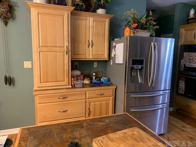 kitchen featuring stainless steel fridge, double oven, light brown cabinetry, and hardwood / wood-style floors