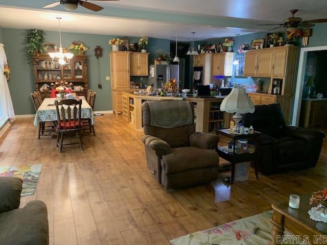 living room with light hardwood / wood-style floors and ceiling fan with notable chandelier