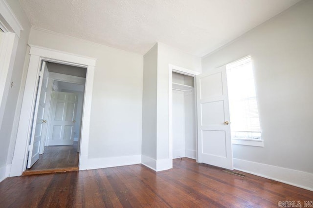 unfurnished bedroom with a closet, dark hardwood / wood-style floors, and a textured ceiling