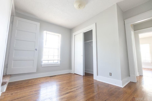 unfurnished bedroom with a closet, dark hardwood / wood-style floors, and a textured ceiling