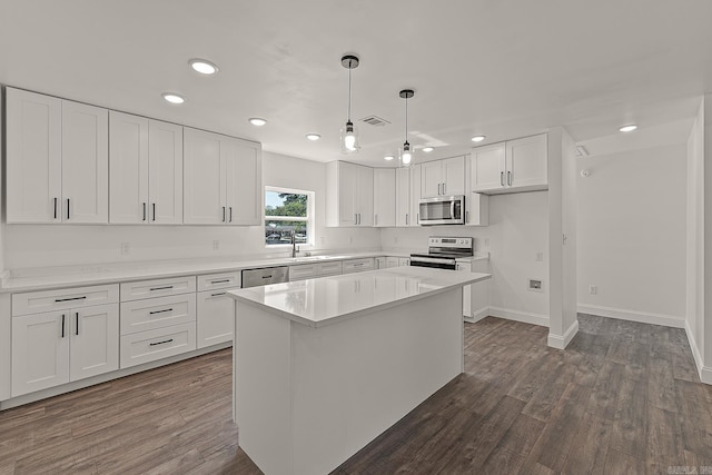 kitchen with appliances with stainless steel finishes, white cabinetry, a center island, and decorative light fixtures