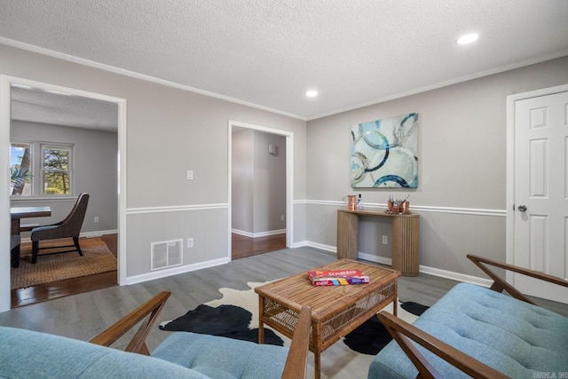 living room featuring ornamental molding, a textured ceiling, and dark wood-type flooring