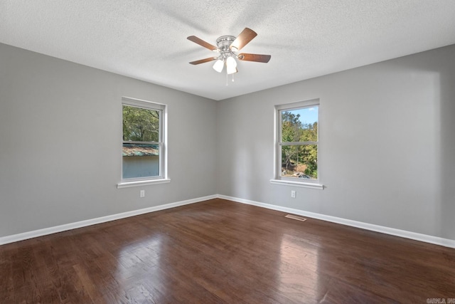 spare room with dark hardwood / wood-style flooring, a wealth of natural light, and a textured ceiling