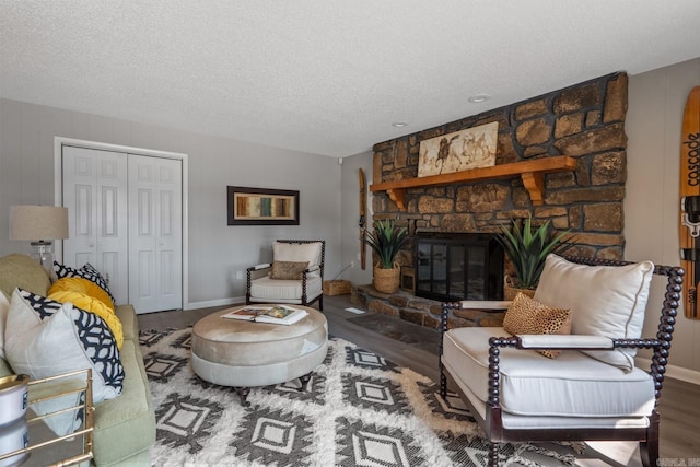 living room featuring hardwood / wood-style floors, a textured ceiling, and a stone fireplace