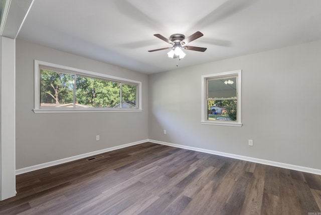 spare room with dark hardwood / wood-style flooring, a wealth of natural light, and ceiling fan