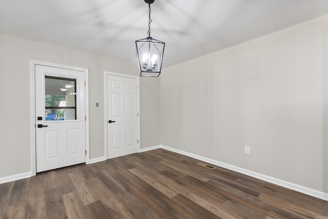 foyer featuring dark wood-type flooring and a chandelier