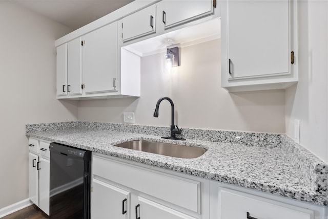 kitchen featuring light stone counters, black dishwasher, sink, and white cabinetry