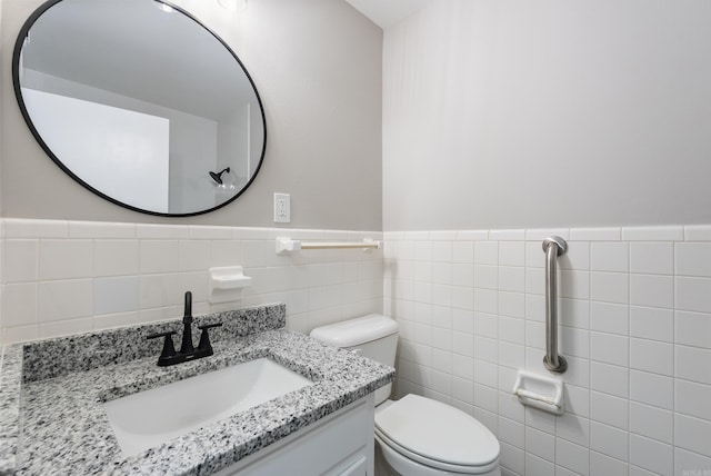 bathroom featuring vanity, tile walls, and toilet