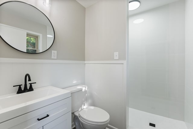 bathroom featuring a tile shower, vanity, and toilet