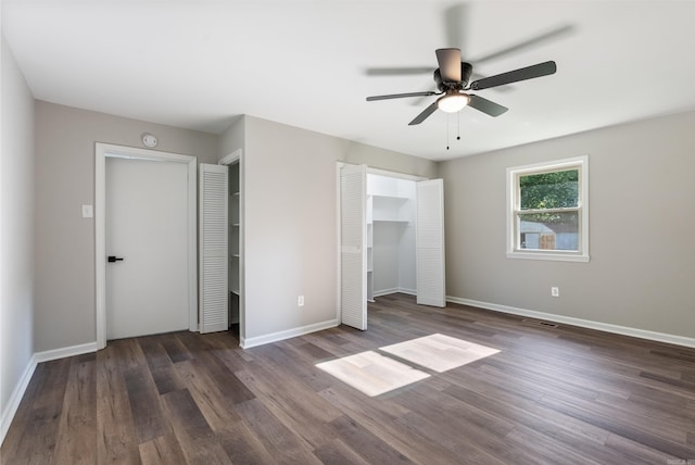 unfurnished bedroom with ceiling fan, multiple closets, and dark hardwood / wood-style floors