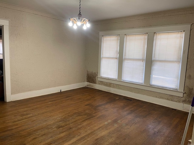 unfurnished room featuring a chandelier, ornamental molding, and dark wood-type flooring