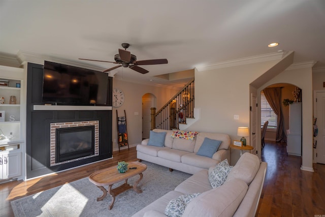 living room featuring a brick fireplace, ornamental molding, ceiling fan, and dark hardwood / wood-style flooring