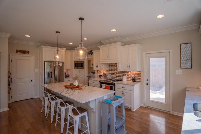 kitchen with white cabinets, stainless steel appliances, hardwood / wood-style floors, and pendant lighting