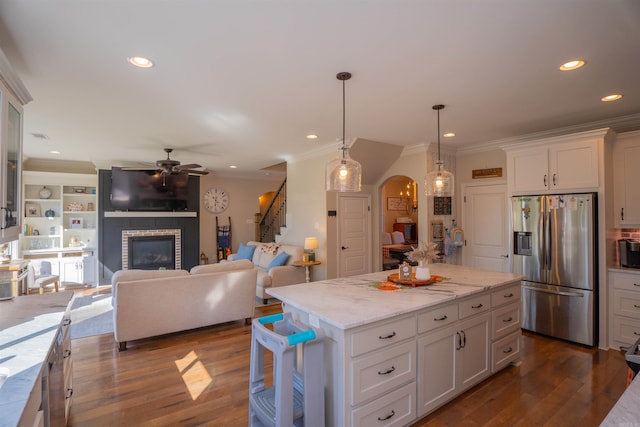 kitchen featuring stainless steel fridge, white cabinets, hanging light fixtures, dark hardwood / wood-style flooring, and a kitchen island