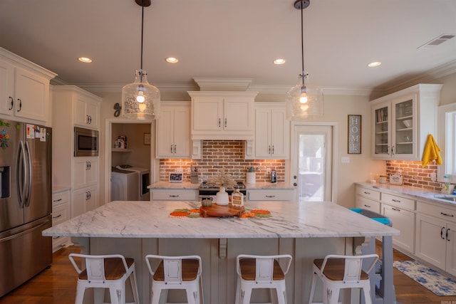 kitchen featuring a kitchen island, appliances with stainless steel finishes, washer and dryer, and white cabinetry