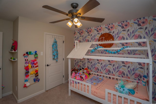 carpeted bedroom featuring a nursery area and ceiling fan