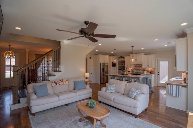 living room featuring sink, crown molding, wood-type flooring, and ceiling fan with notable chandelier