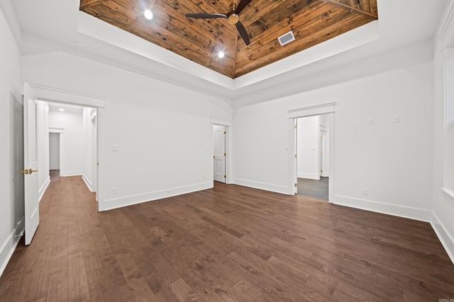 spare room featuring a towering ceiling, a tray ceiling, ceiling fan, dark wood-type flooring, and wooden ceiling