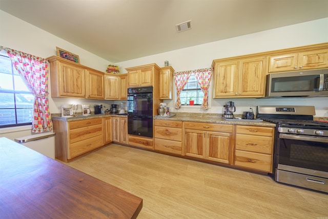 kitchen featuring stainless steel appliances, light wood-type flooring, and vaulted ceiling