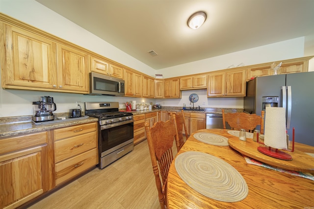 kitchen with sink, appliances with stainless steel finishes, and light hardwood / wood-style floors