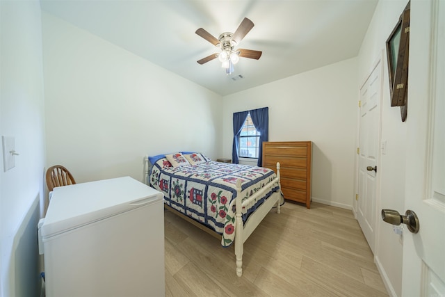 bedroom featuring light hardwood / wood-style floors, fridge, and ceiling fan