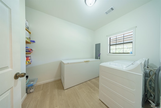 laundry area featuring electric panel, light wood-type flooring, and independent washer and dryer