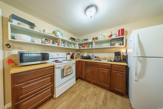 kitchen with wooden counters, white appliances, sink, and light hardwood / wood-style flooring