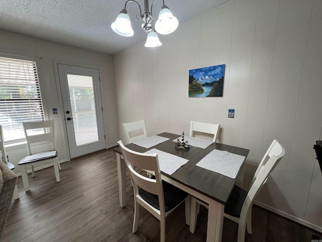 dining area featuring dark wood-type flooring, wooden walls, and a textured ceiling