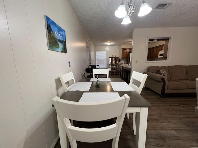 dining space featuring hardwood / wood-style floors, a chandelier, and a textured ceiling