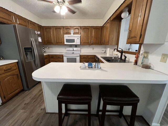 kitchen featuring white appliances, a kitchen breakfast bar, sink, and a textured ceiling